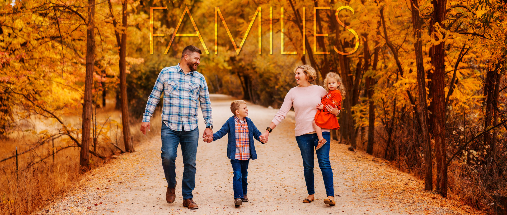 Family of four walks down autumn path by Eagle River Greenbelt on family photo session in Boise Idaho