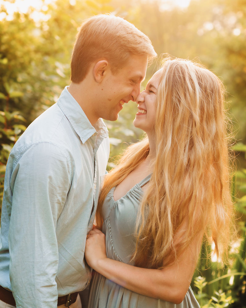 Young couple giggling while nose-to-nose at sunset on engagement photoshoot at Boise's Kathryn Albertson Park