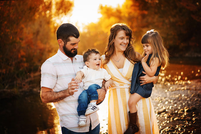 Family of four with two young children taking family photos by Boise River in Eagle, Idaho