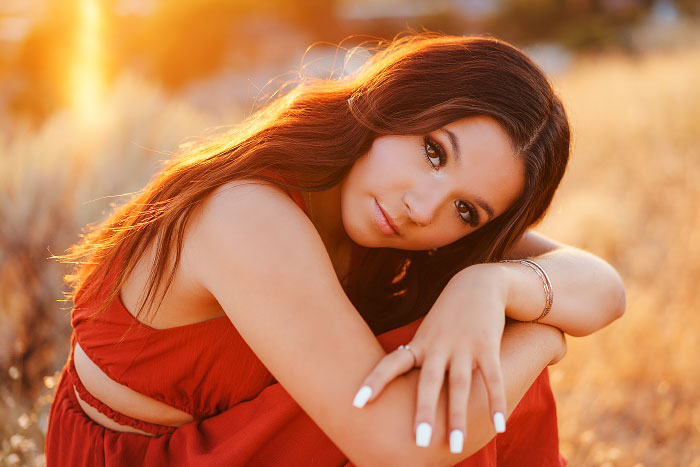 Portrait of high school senior girl resting head on hands in Boise Idaho foothills at sunset