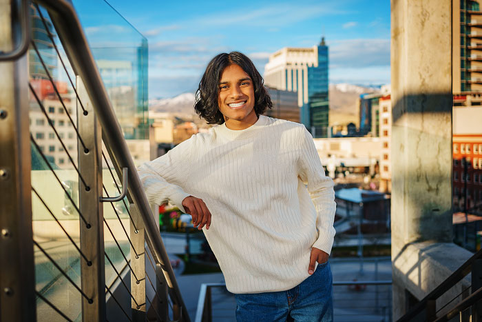 Senior portrait of young man standing on staircase with downtown Boise in background