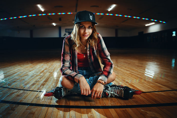 High school girl wearing roller blades sitting crosslegged on roller rink in Nampa Idaho