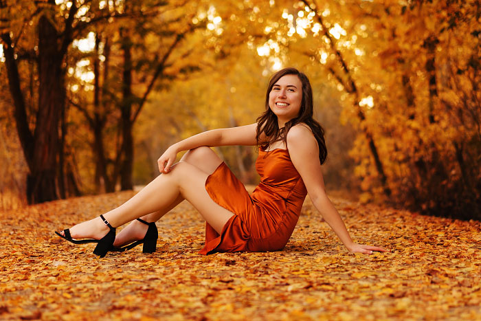 Teenage girl sits on leaf-covered path on Eagle Greenbelt outside Boise, Idaho