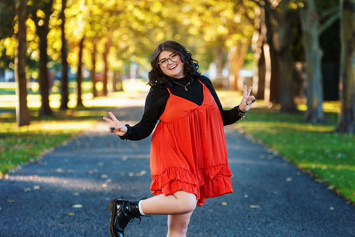 Teen girl flashes peace sign in high school senior photo in Julia Davis Park, Idaho