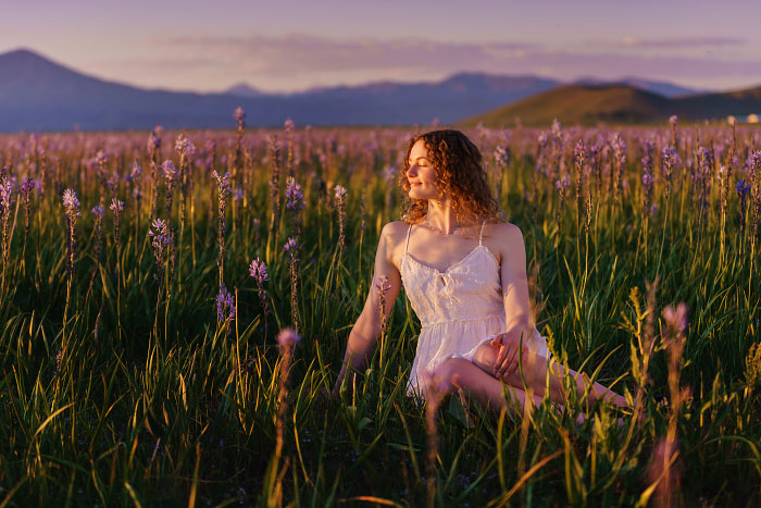 Girl in white dress sits in field of camas lilies at sunset at Centennial Marsh Idaho