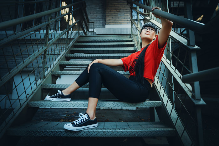 Teen girl sits on staircase for senior photos