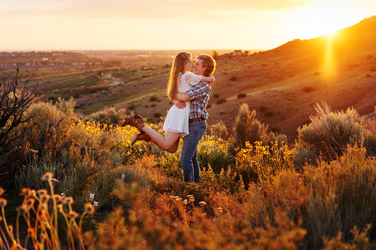 Teen boy picks up girl in meadow of flowers in southeast Boise