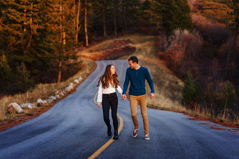 Couple walks hand in hand up forested road in mountains outside Boise