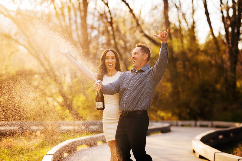 Man and woman pop bottle of champagne for anniversary photoshoot celebration at Kathryn Albertson Park in Boise