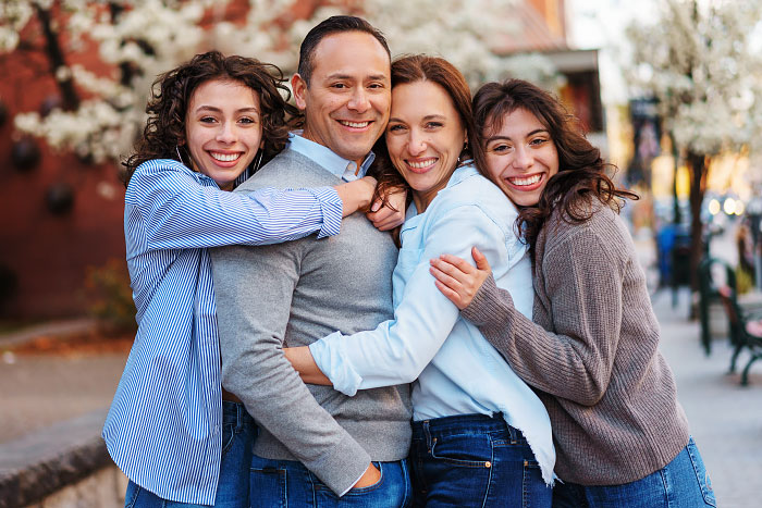 Family of four with two teenage daughters in group hug for family photoshoot