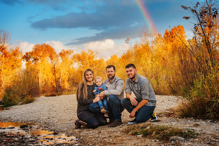 Family of four on banks of Boise River with rainbow in background in fall