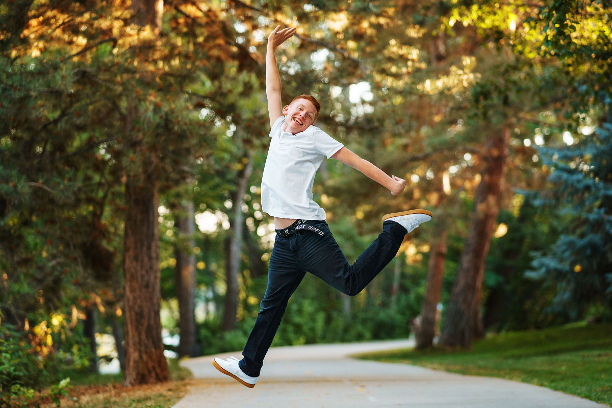 High school senior boy jumping on Boise Greenbelt for senior photos