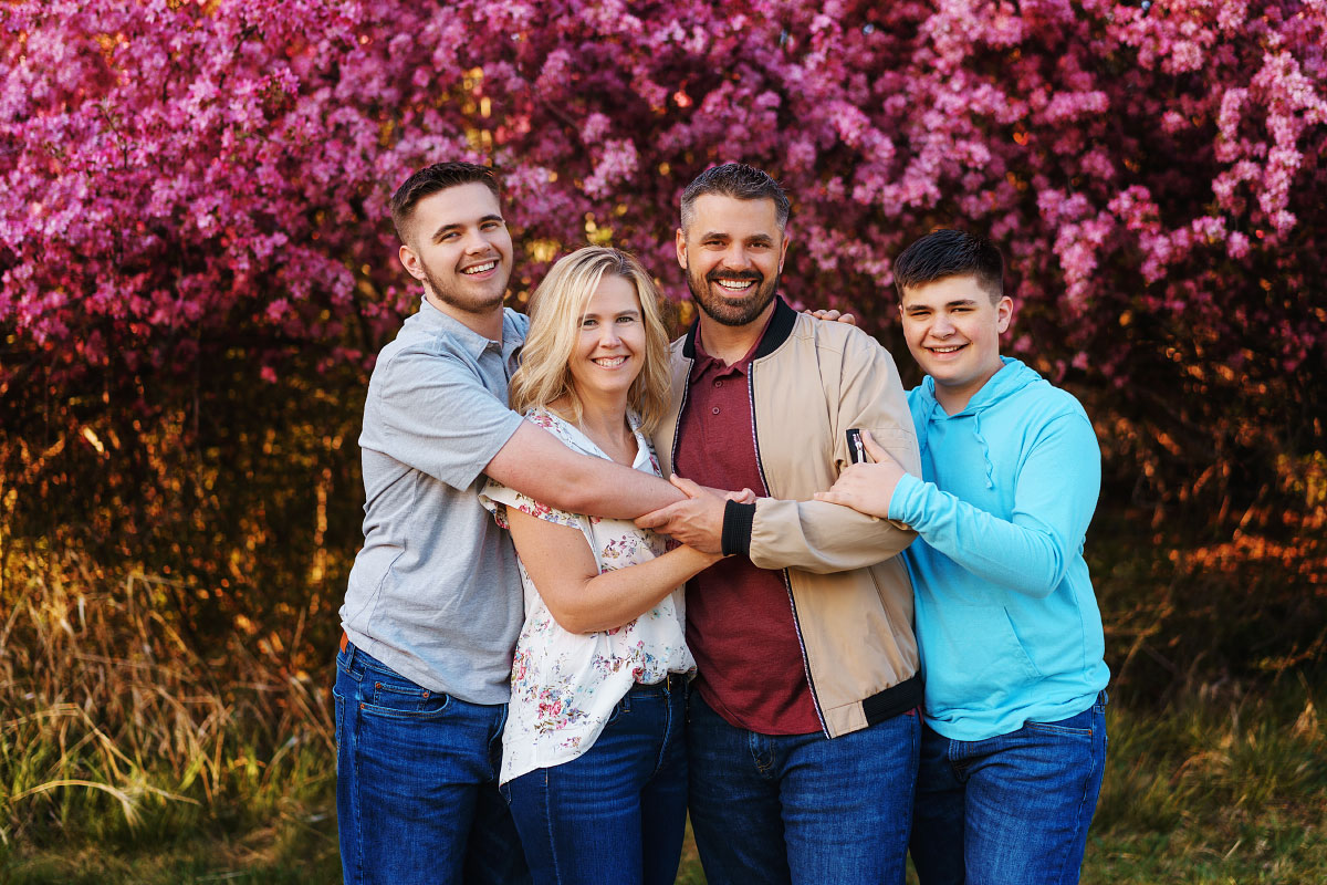 Group family hug against background of pink blossoms at Kathryn Albertson Park in Boise
