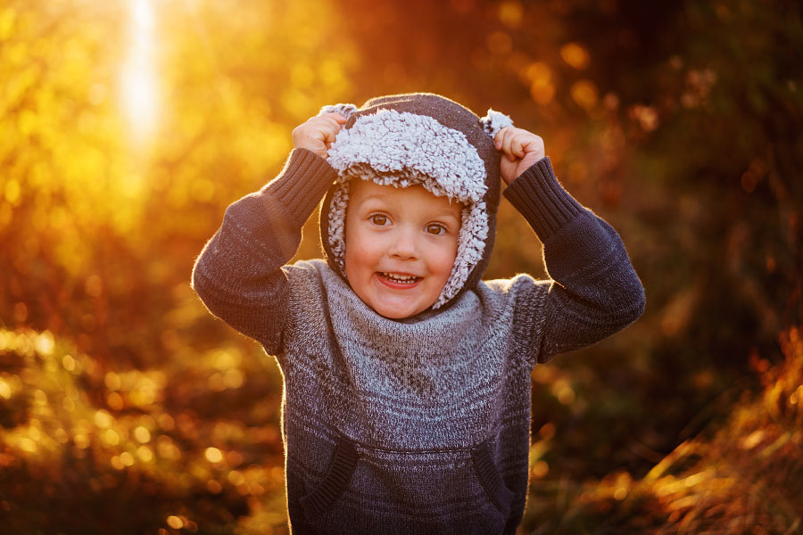 Little boy in fluffy hood making silly face at camera for family photos
