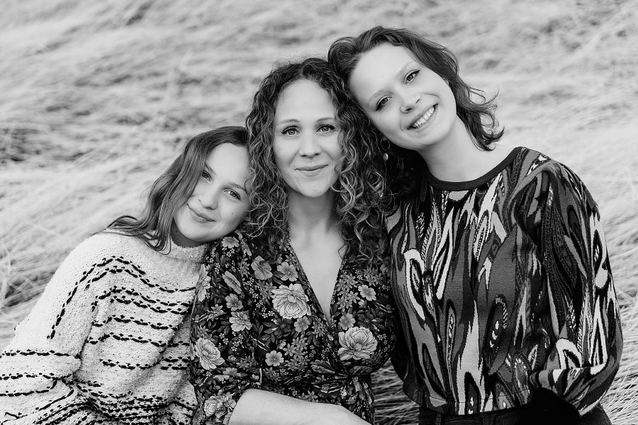 Portrait of mother and teenage daughters resting their heads together in black and white family picture